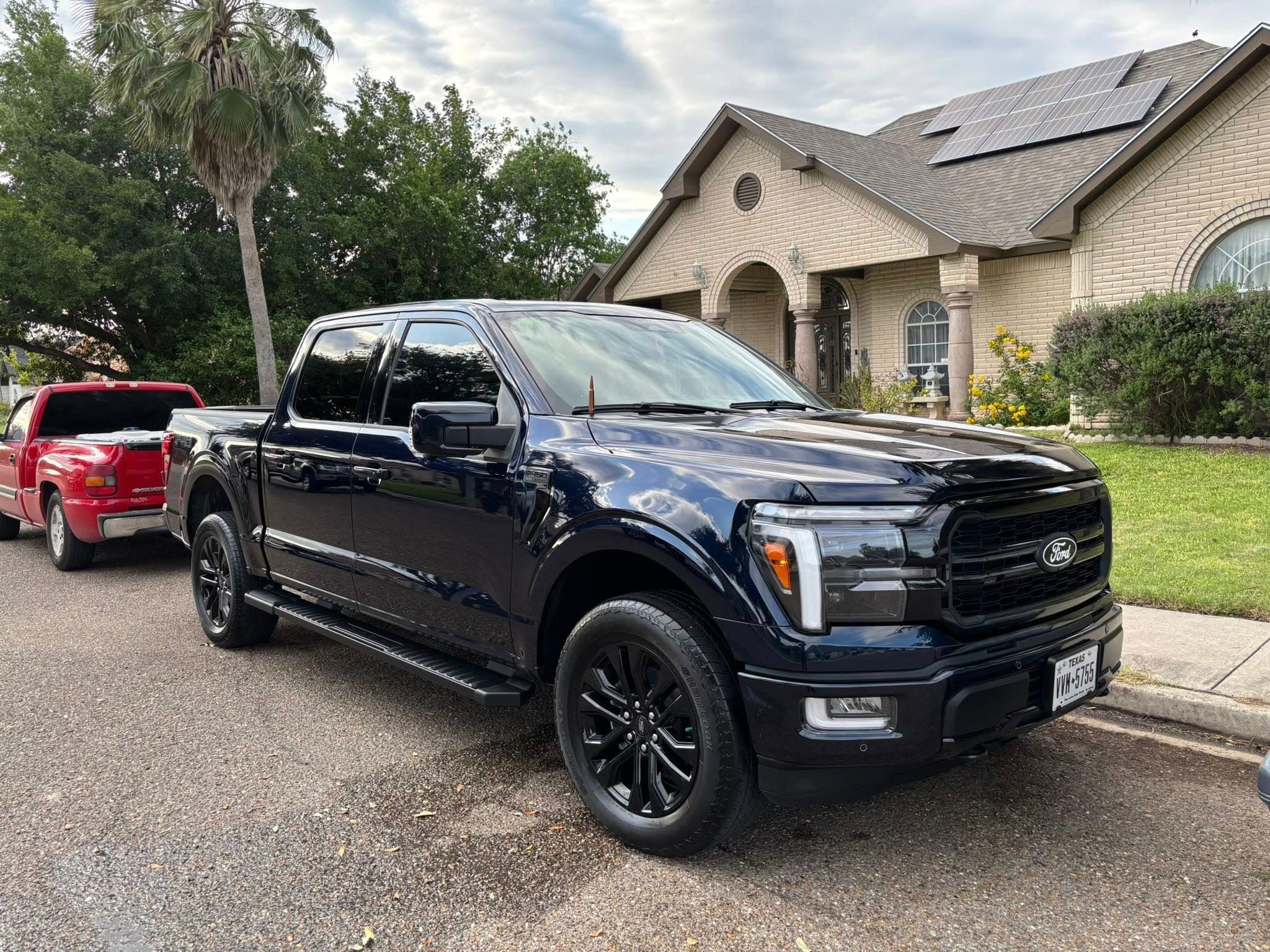 Black Ford F-150 pickup gleaming in a residential driveway after a hand wash
