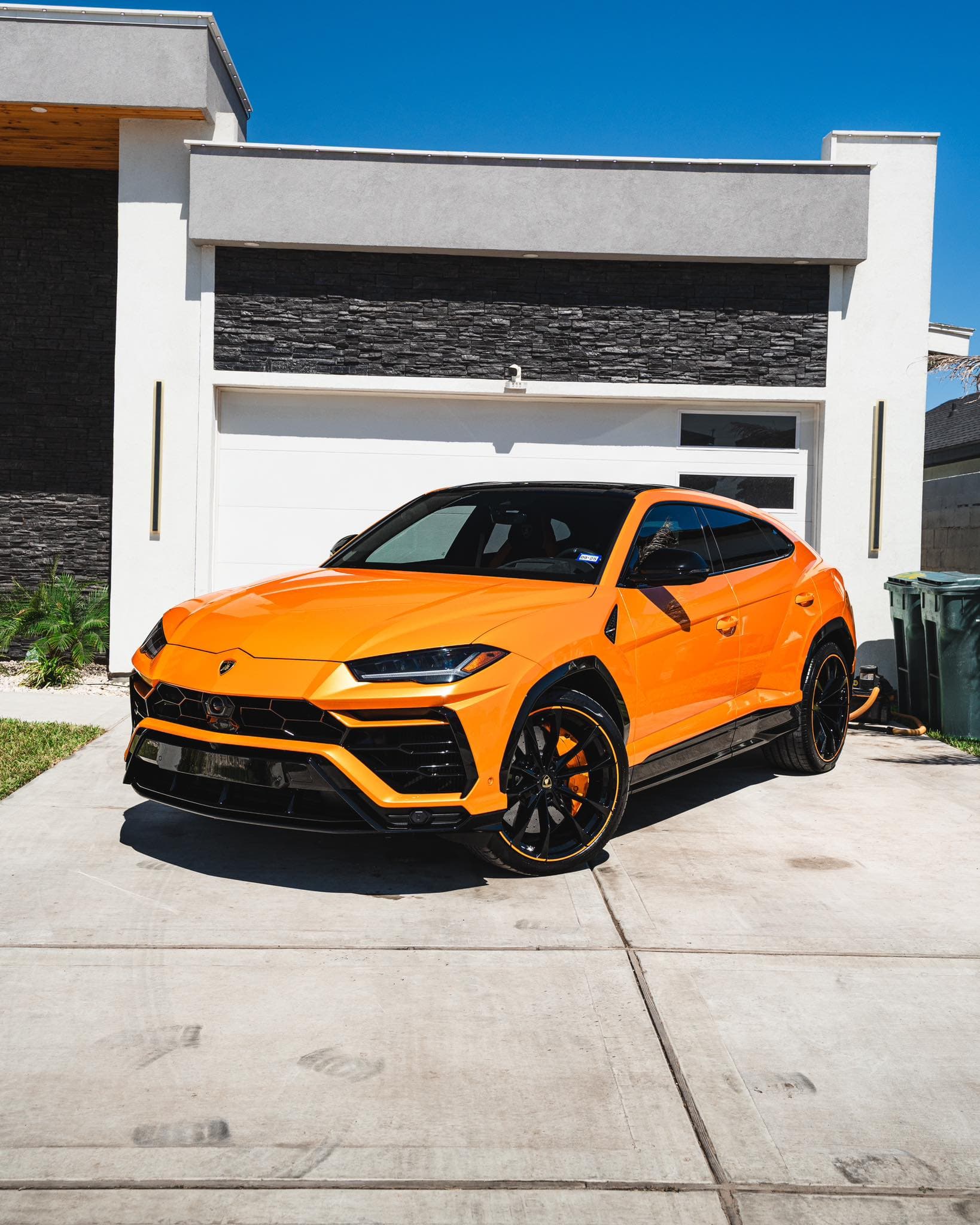 Orange Lamborghini Urus freshly detailed in a driveway, paint gleaming in full sun